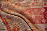 Textured pile of the vintage Oushak runner with red, blush, and sand border motifs.