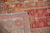 Distressed Oushak runner's worn red-orange pile, visible foundation, and striped reverse weave.