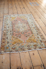 Upper right detail of distressed Oushak rug, showing faded saffron, seafoam, and sandalwood palmette motifs.