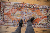 Distressed Oushak runner showing knot heads, with pale tangerine orange and faded royal blue designs.