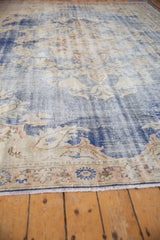 Close-up of distressed vintage Oushak rug, featuring worn denim blue pile, visible foundation, and fringed border.