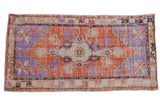 Vintage distressed Oushak runner with a tangerine orange field, floral medallion, and faded blue accents.