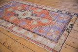 Angled view of the distressed texture on a tangerine orange and royal blue Oushak runner.