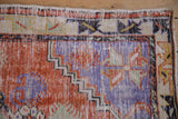 Close-up of the vintage Oushak's low pile, revealing its ivory foundation and colorful motifs.