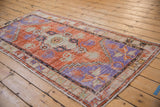 Angled view of a distressed Oushak runner showing its worn texture and tangerine orange and royal blue design.
