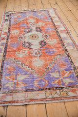 Distressed Oushak runner shown at an angle, with a tangerine, blue, and seafoam green medallion.