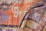 Folded view of a vintage Oushak rug showing distressed, low-pile texture with visible knot heads.