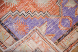 Folded corner of a distressed Oushak rug showing its hand-knotted foundation and low-cut pile.