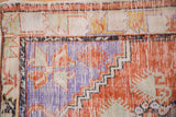 Worn texture and pinwheel corner spandrel in tangerine, blue, and ivory on a vintage Oushak.