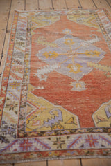 Detail of distressed Oushak rug, showing burnt orange pile, faded blue palmettes, and knot head wear.