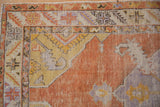 Distressed burnt orange field and serrated border detail of a vintage Oushak rug.
