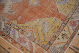Distressed vintage Oushak rug detail with burnt orange field, saffron spandrel, serrated leaf border.