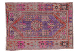 Distressed vintage Oushak rug with geometric stepped medallion, pops of pink, purple, terra cotta.