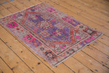 Distressed vintage Oushak rug showing worn pile with vibrant pink and purple patterns.