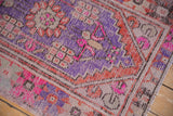 Distressed vintage Oushak rug, close-up of geometric floral motifs in fuchsia, lavender, terra cotta.