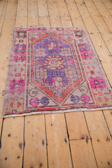 Distressed pink, purple, and terra cotta geometric patterns on a vintage Oushak rug.