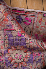 Distressed Oushak rug pile texture with vibrant pink, purple, terra cotta hues, visible wear, and fringe.