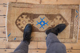 Distressed Oushak mat texture with vibrant blue geometric motif and earthen tones.