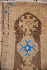 Textured distressed Oushak rug with geometric brown and vibrant blue pattern, showing side selvage.