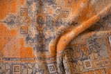 Textural detail of a distressed Oushak rug with tangerine, charcoal, and beige pile.