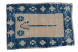 Distressed vintage Oushak rug mat with a central blue plant and ivory geometric border.