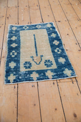Distressed indigo blue Oushak rug corner showing geometric floral motifs and ivory field.
