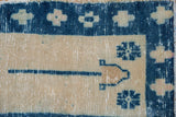 Close-up of distressed Oushak rug with cobalt geometric floral motifs on pale ivory.