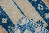 Distressed Oushak rug corner detail, showing worn pale ivory, cobalt geometric floral pile, and foundation.