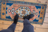Distressed Oushak rug mat with softened sandalwood and cobalt blue floral medallion.