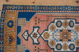 Corner view of vintage distressed Oushak rug with cobalt blue and pink floral border.