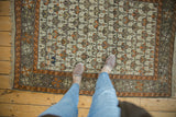 Antique Caucasian rug's end showing geometric motifs in ivory, tangerine, mauve, and intact fringe.