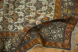 Caucasian rug detail: geometric ivory and mauve field, tangerine border, with original macrame fringe.