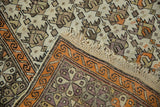 Intact macrame fringe with geometric tangerine border on an antique Caucasian rug.