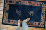 Feet on vintage Chinese Art Deco rug, showing blue field, floral motifs, and visible knot heads.