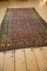 Vintage Kurdish Bijar rug close-up showing saffron yellow border and spiraled floral motifs.