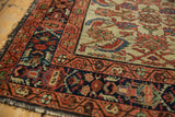Vintage Hamadan rug corner with dark fringe, displaying intricate rust-red and indigo border motifs.