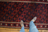 A personal view of an antique Belouch rug's intricate lattice pattern in madder red and deep blue.