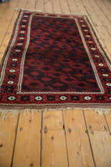 A perspective view down the length of an antique Belouch rug, showcasing its tribal lattice design.