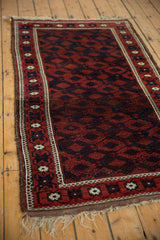 Angled perspective of an antique Belouch rug, showing its full length, lattice design, and bordered edges.