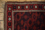 Corner of an antique Belouch rug with its intact plain weave, fringe, and geometric border.