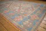 Distressed Soumac rug showing halved medallion, floral border in muted blue and coral.