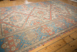 Distressed texture of vintage Soumac carpet, with geometric patterns and floral border.
