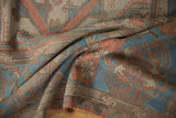 Folded detail of vintage distressed Soumac carpet, showing handwoven texture and muted geometric motifs.