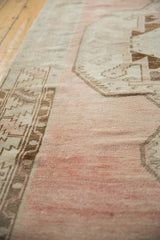 Distressed Oushak runner, pale dusty raspberry abrashed field with serrated coffee brown border.