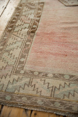 Distressed vintage Oushak runner's serrated border in brown and silver with abrashed dusty rose field.