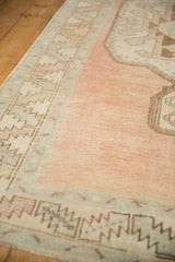 Abrashed dusty raspberry field with worn serrated leaf border of a vintage Oushak runner.