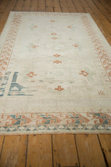 Distressed Oushak rug's geometric arabesque border in ivory, copper, and dusty navy.