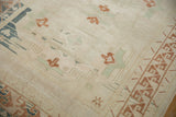 Distressed Oushak rug's ivory pile, showing copper geometric border and pale seafoam motifs.