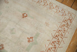 Distressed vintage Oushak rug pile with chestnut brown geometric border and faded seafoam motifs.