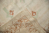 Distressed Oushak rug corner revealing worn pile, side selvage, and geometric foundation pattern.